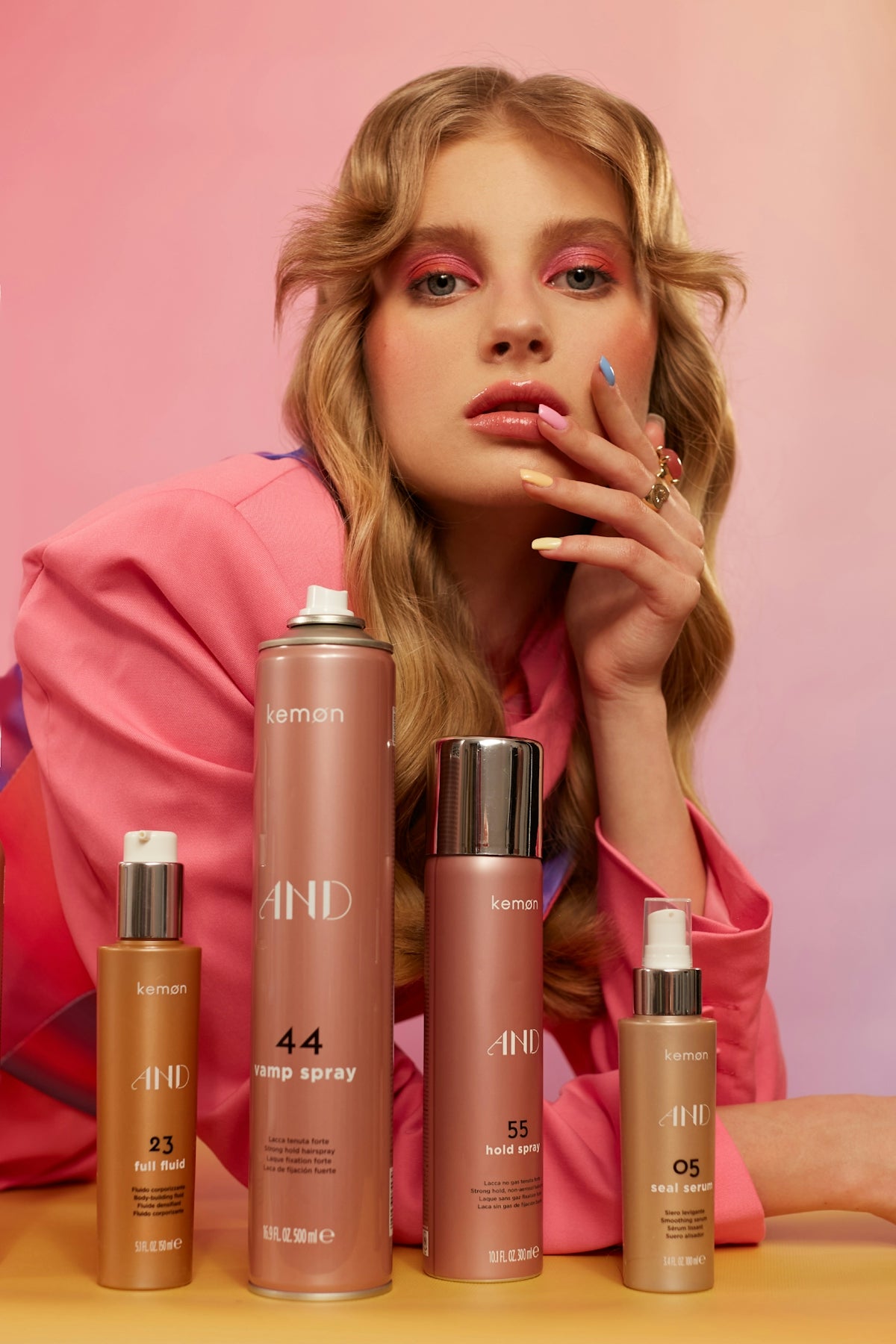 A woman with wavy hair poses with four beauty products.